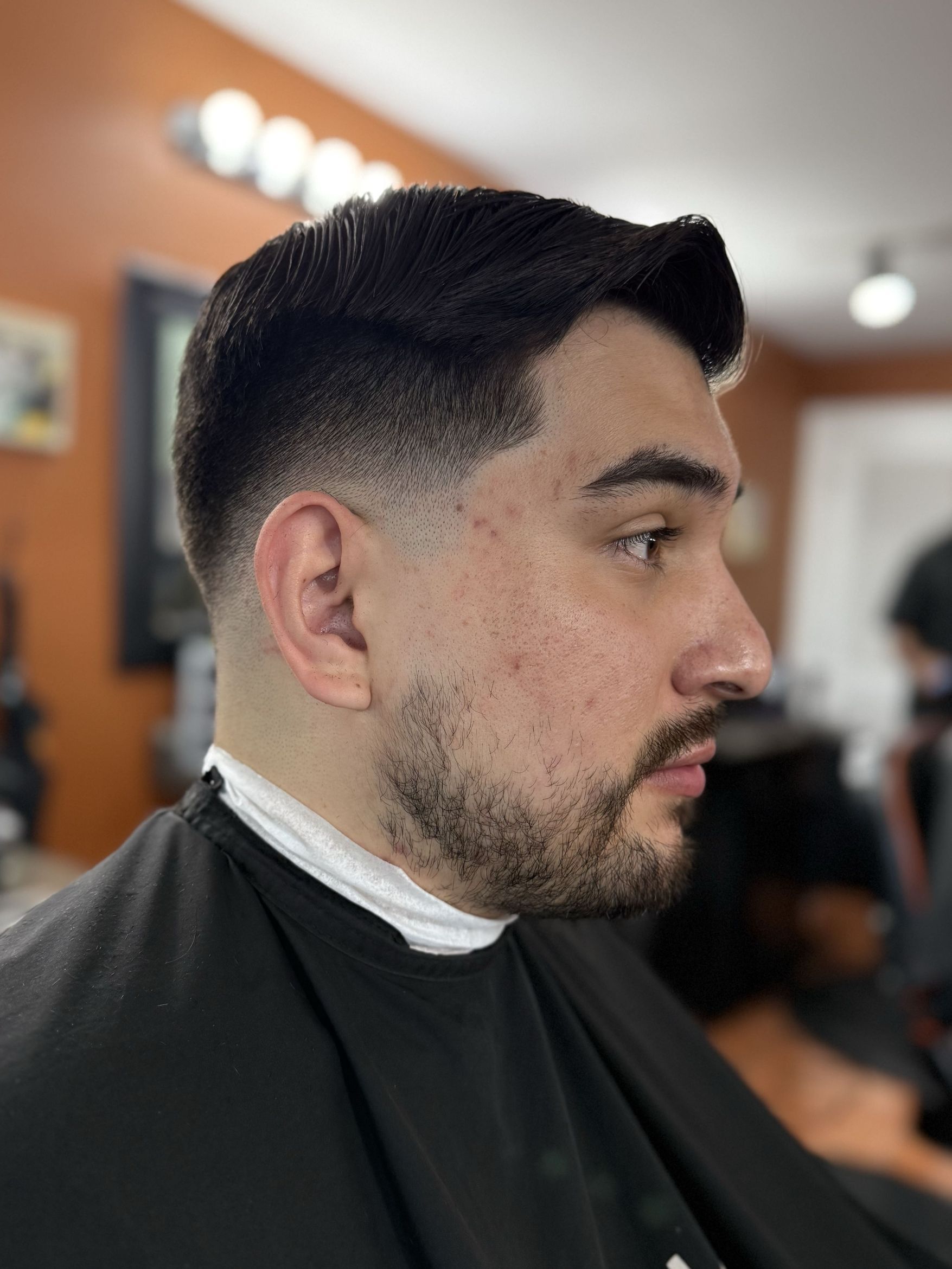 Side-part comb-over with low fade and beard by Rich — Rocky's Primetime Barbershop Atlanta